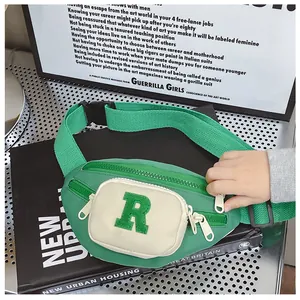 Detail of green nylon waist bag with towel-embroidered R letter on black books