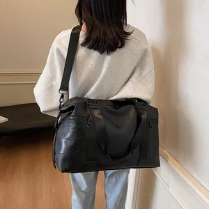 Große schwarze Reisetasche aus Leder mit geometrischen Nähten und verstellbarem Schultergurt