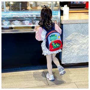 Bambina indossa zaino dinosauro blu e rosso con tasche laterali a rete in gelateria
