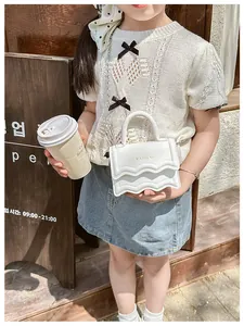 Détail du mini sac blanc pour fille avec rabat ondulé et logo de lettres dorées