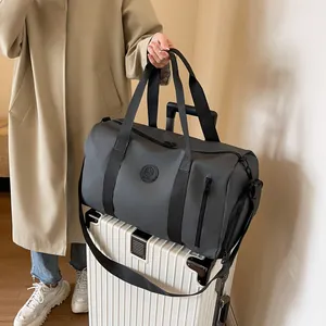 Detail of grey travel bag with circular logo and shoe compartment on white suitcase