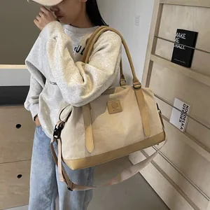 Detail of beige canvas travel bag with leather accents and adjustable shoulder strap