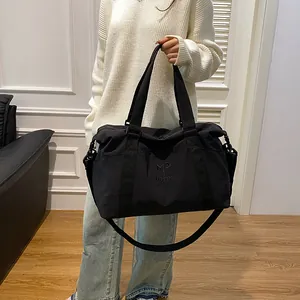 Dettaglio di una borsa da viaggio nera capiente con logo ricamato e tracolla ampia