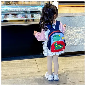 Vista posteriore di un bambino con zaino dinosauro blu e rosso e tasche laterali in rete