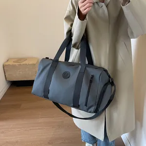 Detail of grey-blue gym bag showing brand logo, side zipper and detachable shoulder strap