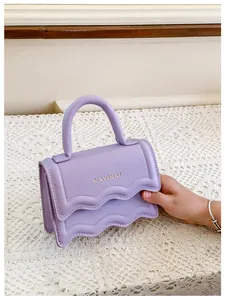 Détail du mini sac bandoulière lilas avec bords ondulés et lettrage doré chic