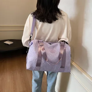 Close-up of purple travel bag with pleated texture and adjustable nylon shoulder strap