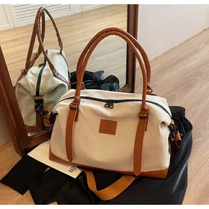 Close-up of cream canvas travel bag with brown leather handles and NINGJIA logo patch