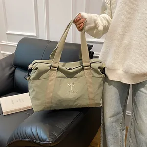 Dettaglio borsa da viaggio verde salvia con manici robusti e anelli a D in metallo