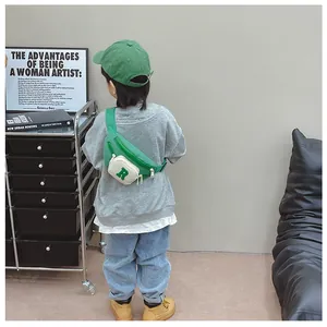 Rear view of a child wearing a green crossbody chest bag with ivory pocket and letter R