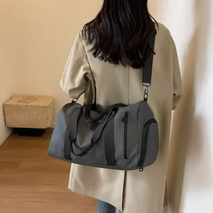 Detail of grey travel bag with waterproof fabric and adjustable shoulder strap on a model