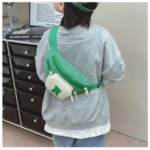 Close-up of a green nylon kids chest bag with letter R patch worn by a child in style