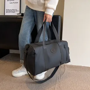 Detail view of large black waterproof travel bag with a side shoe compartment and logo