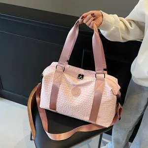 Pink large travel bag with quilted texture and ZSSJ logo held by a model on dark background