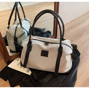 Close-up of beige canvas travel bag with black leather accents and dual zippers