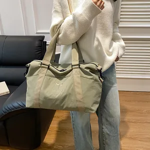 Dettaglio della borsa da viaggio verde con manici e logo in un ambiente lifestyle