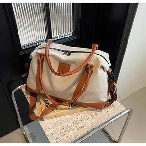 Detail view of the large canvas travel bag showing the brown leather handles and base