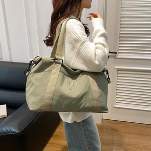 Dettaglio di una grande borsa da viaggio verde fagiolo con logo ricamato e tracolle
