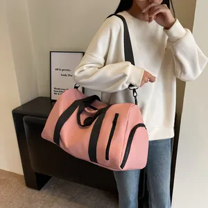 Pink nylon travel bag with shoe compartment shown as a crossbody on a female model