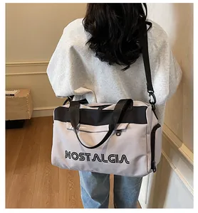 Detail of grey travel bag featuring adjustable shoulder strap and nostalgia lettering