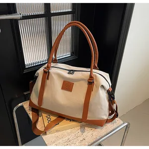 Detail of canvas travel bag with leather trim, Mingda logo, and adjustable shoulder strap