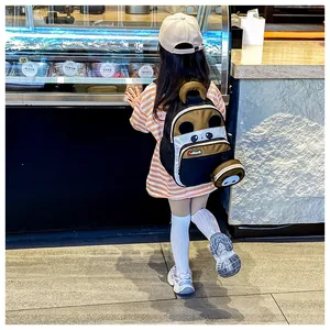 Kid's panda backpack with matching coin purse shown on a child in a shop setting