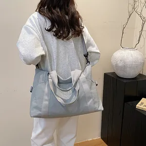 Dettaglio di una borsa da viaggio blu con manici intrecciati e dettagli del logo MOPPO