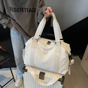 Close-up of white textured travel bag with wide handles placed on top of a suitcase