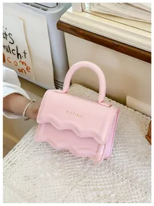 Détail du mini sac à main rose avec rabat à double épaisseur et lettrage doré chic