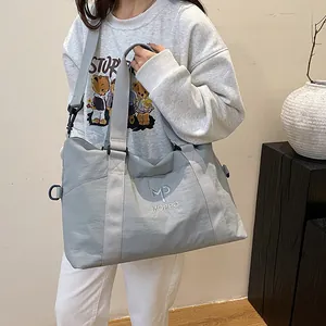 Dettaglio della borsa da viaggio grigia in nylon capiente con ricamo distintivo