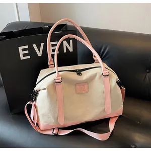 Detail of canvas travel tote with pink leather handles and detachable shoulder strap