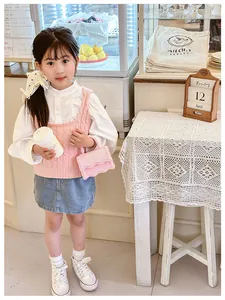 Gros plan du mini sac bandoulière rose associé à une tenue en tricot tendance pour enfant