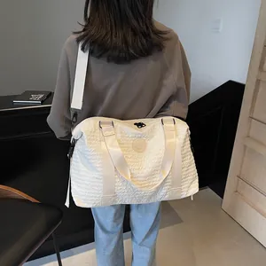 Rear view of a beige quilted travel bag featuring a round logo and adjustable shoulder strap