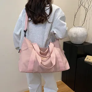 Borsa da viaggio in nylon rosa con tracolla e logo ricamato in un ambiente estetico