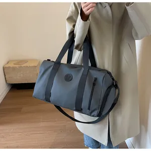 Detail of grey waterproof sports duffel bag showing nylon straps and round logo patch