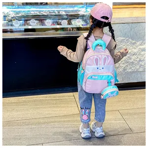 Pink cartoon rabbit backpack with mini coin purse shown on a child for scale