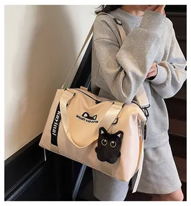 Detail of cute cat graphic and plush charm on a large capacity beige travel tote bag