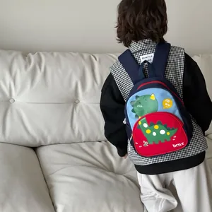 Zaino per bambini con dinosauro in rosso e blu, mostrato indossato da un bambino