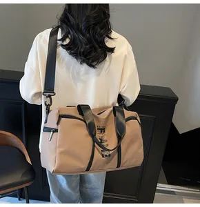 Dettaglio di una borsa sportiva kaki con manici neri e tracolla regolabile