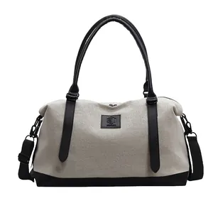 Minimalist canvas travel tote bag with black leather trim and adjustable strap