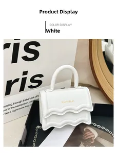 Gros plan d'un mini sac blanc avec rabat à bords ondulés et lettrage doré du logo