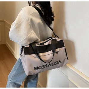 Side view of a grey large-capacity travel bag with black straps worn by a female model