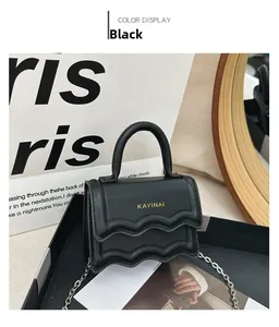 Gros plan d'un mini sac à bandoulière noir avec rabat ondulé et chaîne argentée chic
