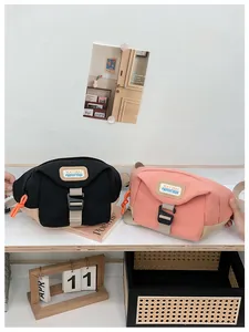Detail showing black and coral pink canvas waist bags with logo and orange zipper cord