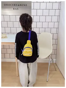 Vue de dos d'un adolescent portant un sac bandoulière en toile jaune et bleu à lettres