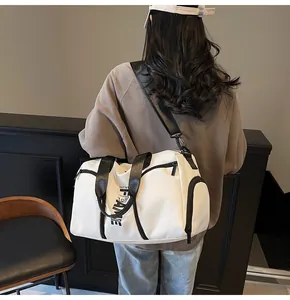 Dettaglio della borsa sportiva bianca con scritte FAME indossata a tracolla dal modello
