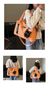 Detail of orange travel bag with cute cat embroidery and plush pendant charm