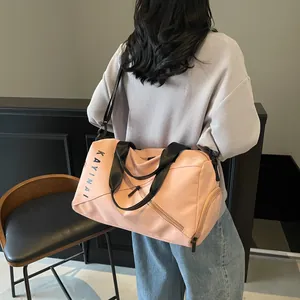Detalle del bolso de viaje rosa con bolsillo lateral, asas negras y logo KAYINAI
