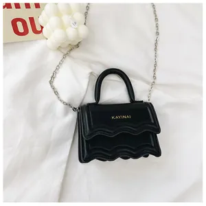 Détail du mini sac bandoulière noir avec bord ondulé et logo de lettres dorées chic