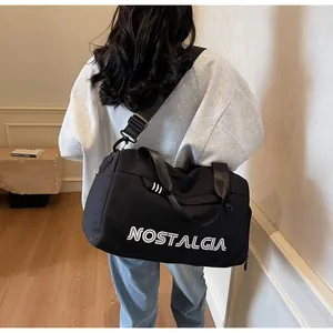 Close-up of black travel bag with white NOSTALGIA lettering and adjustable shoulder strap